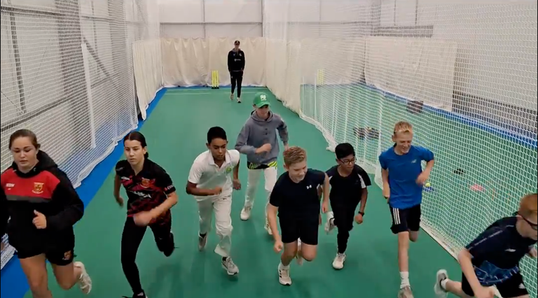 Young cricketers warming up indoors during a Centurion Academy training session at winter nets.